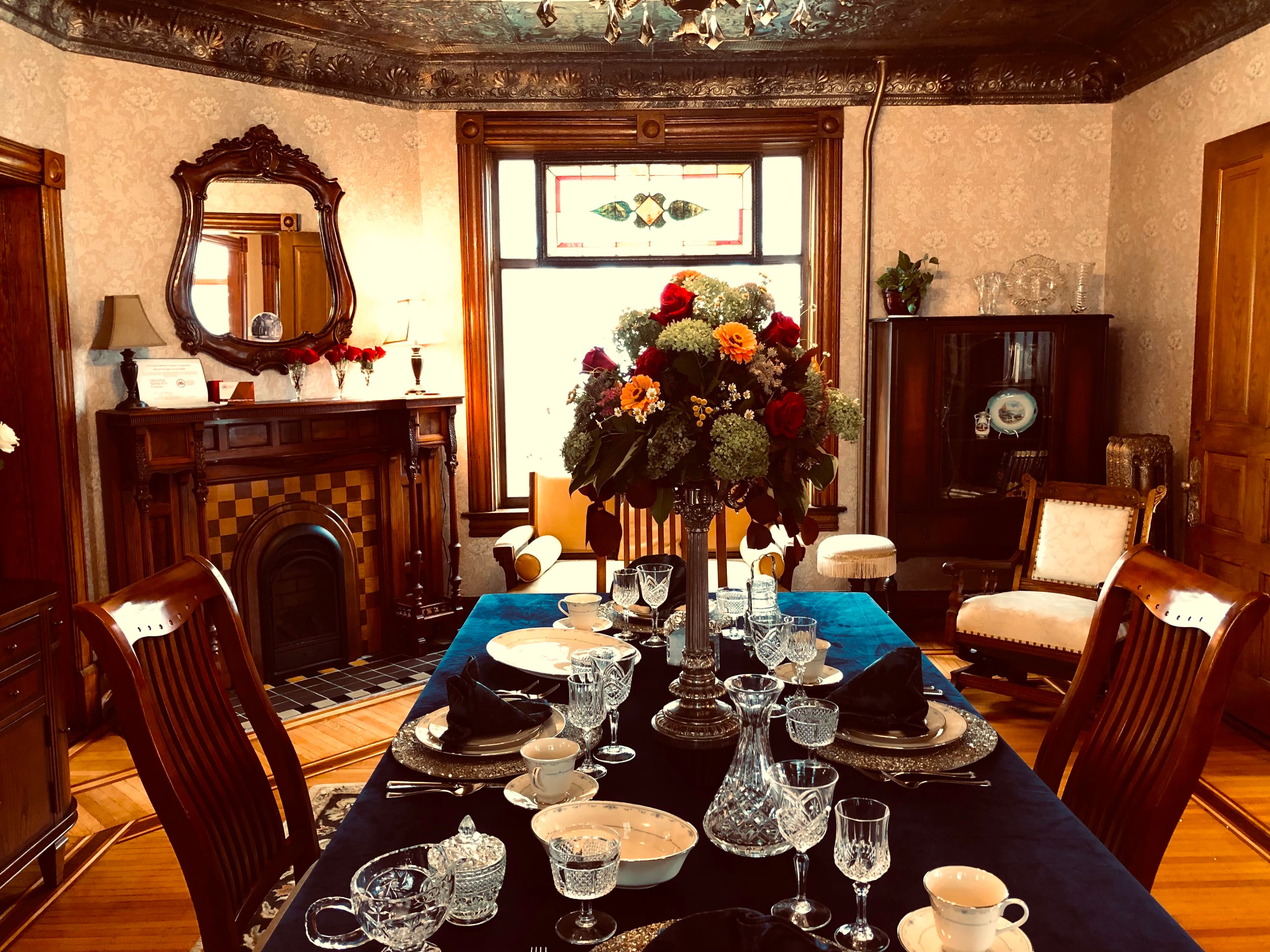 A beautifully set dining table with crystal glassware and a vibrant floral centerpiece in an elegant vintage dining room.