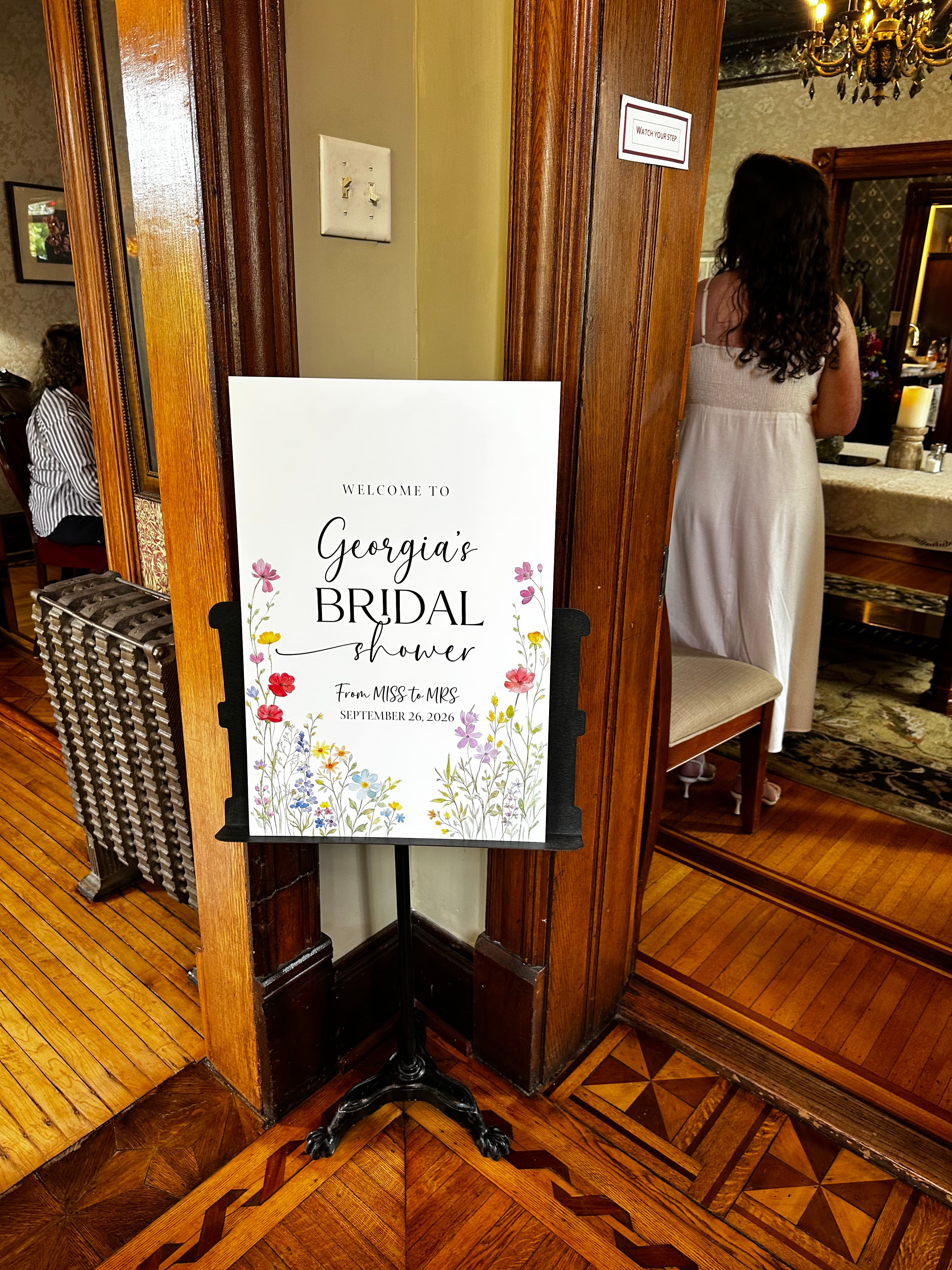 A sign welcoming guests to Georgia's bridal shower, adorned with floral designs.