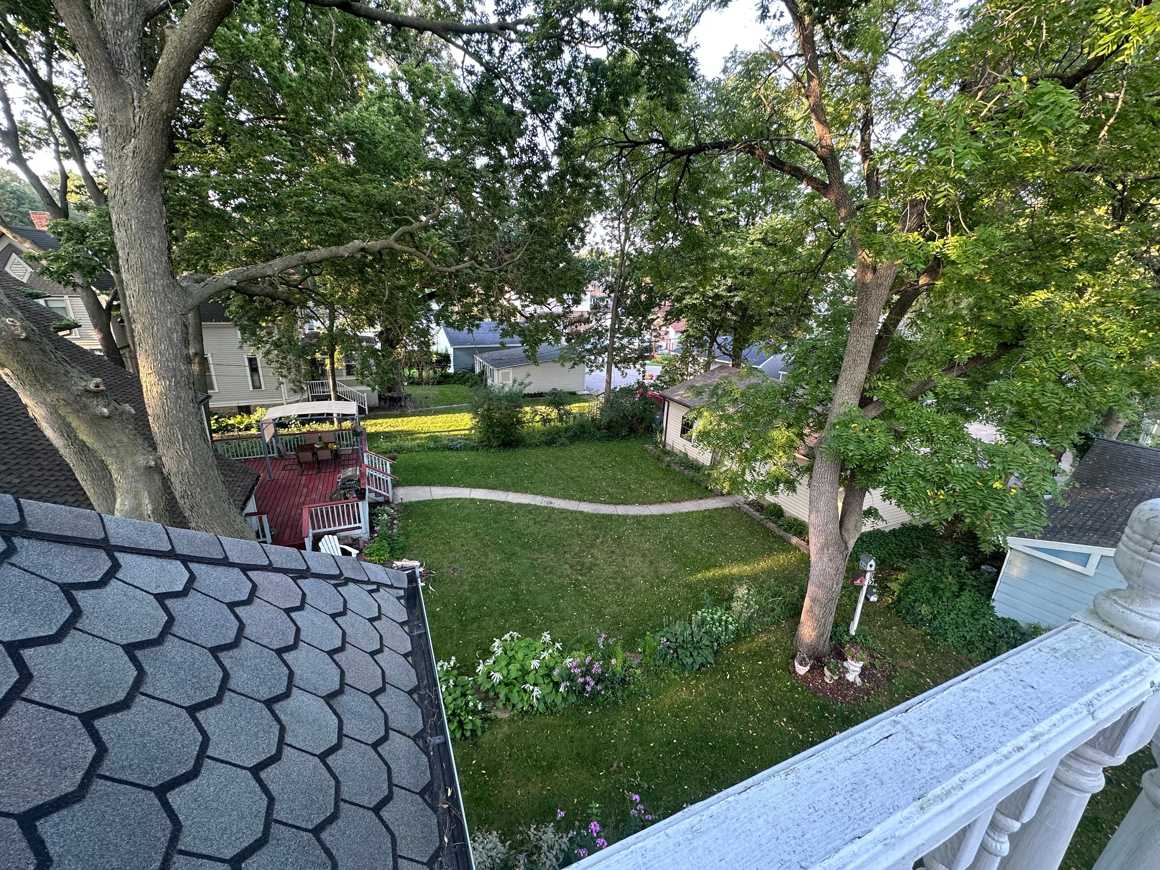 Aerial view of a green backyard with trees, a patio, and flower beds.